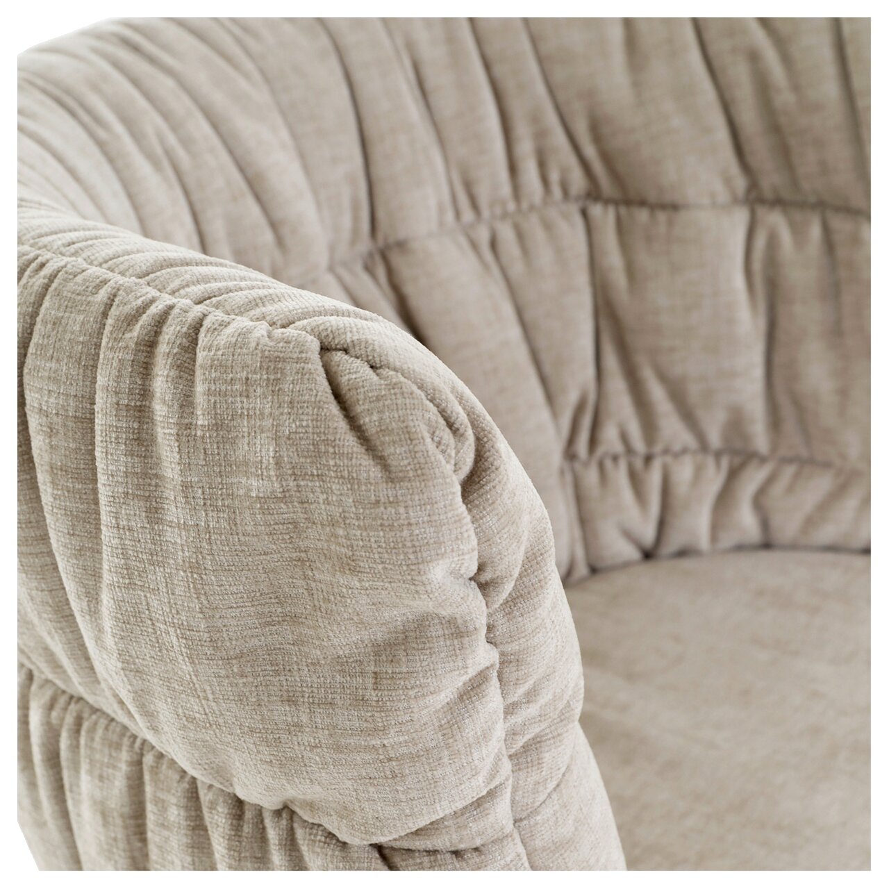 Nahaufnahme eines beigen Armlehnstuhls mit weicher Polsterung und texturierter Oberfläche, seitliche Perspektive.