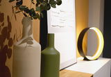 Anschnitt einer Kommode mit zwei Vasen in Beige und Olivegrün. Auf der Kommode steht eine Tischlampe in Form eines RIngs.