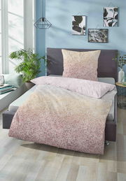 Bett mit Satin-Bettwäsche in sanften Farbverläufen von Beige zu Rosa, fotografiert aus einer seitlichen Perspektive in einem modern eingerichteten Schlafzimmer.