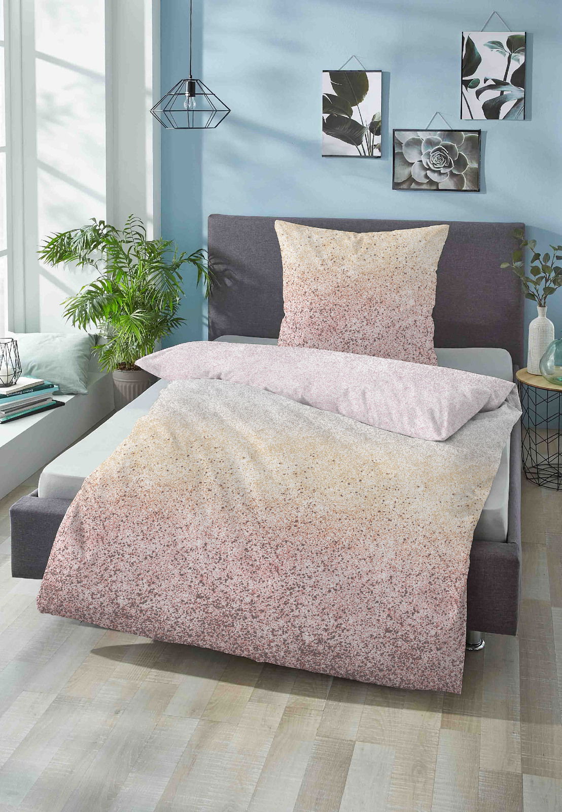 Bett mit Satin-Bettwäsche in sanften Farbverläufen von Beige zu Rosa, fotografiert aus einer seitlichen Perspektive in einem modern eingerichteten Schlafzimmer.