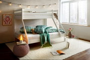 Weißes Etagenbett in einem gemütlichen Schlafzimmer mit Lichterkette, dekorativen Kissen und Decken, aus der Perspektive von vorne rechts.
