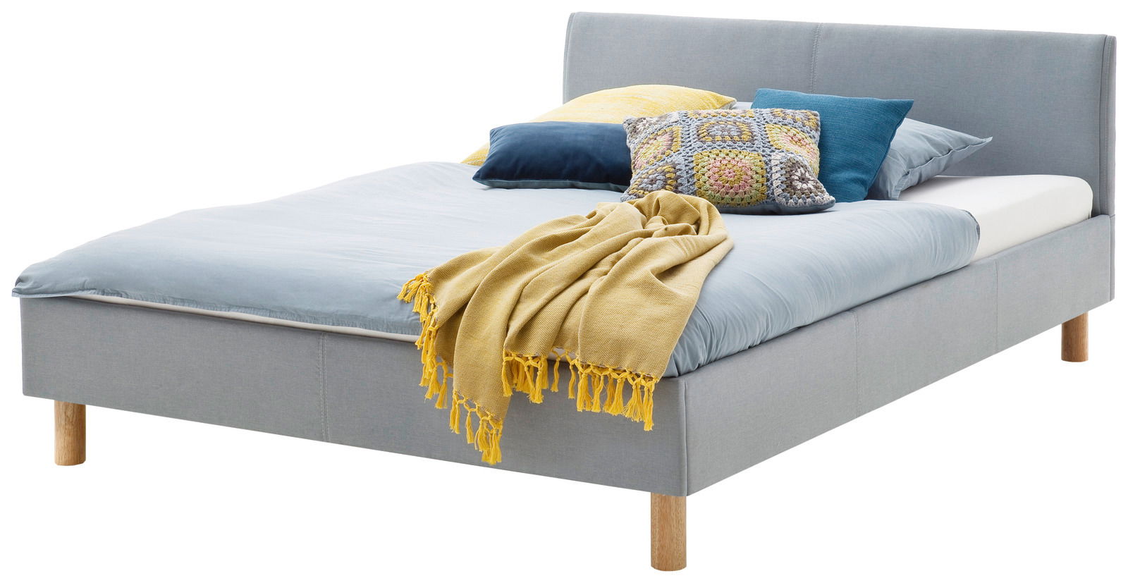 Graues Polsterbett mit Holzfüßen, dekoriert mit bunten Kissen und einer gelben Decke, seitliche Perspektive