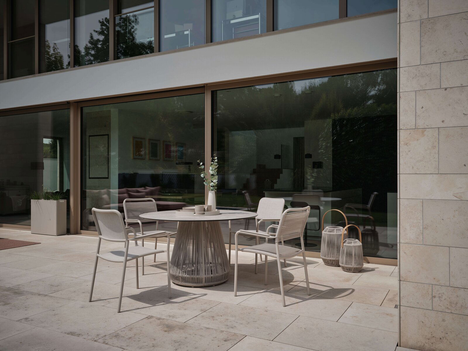 Stern Stapelsessel JORIS Moderner Stapelsessel auf einer Terrasse, seitliche Perspektive, umgeben von einem eleganten Tisch und dekorativen Laternen.