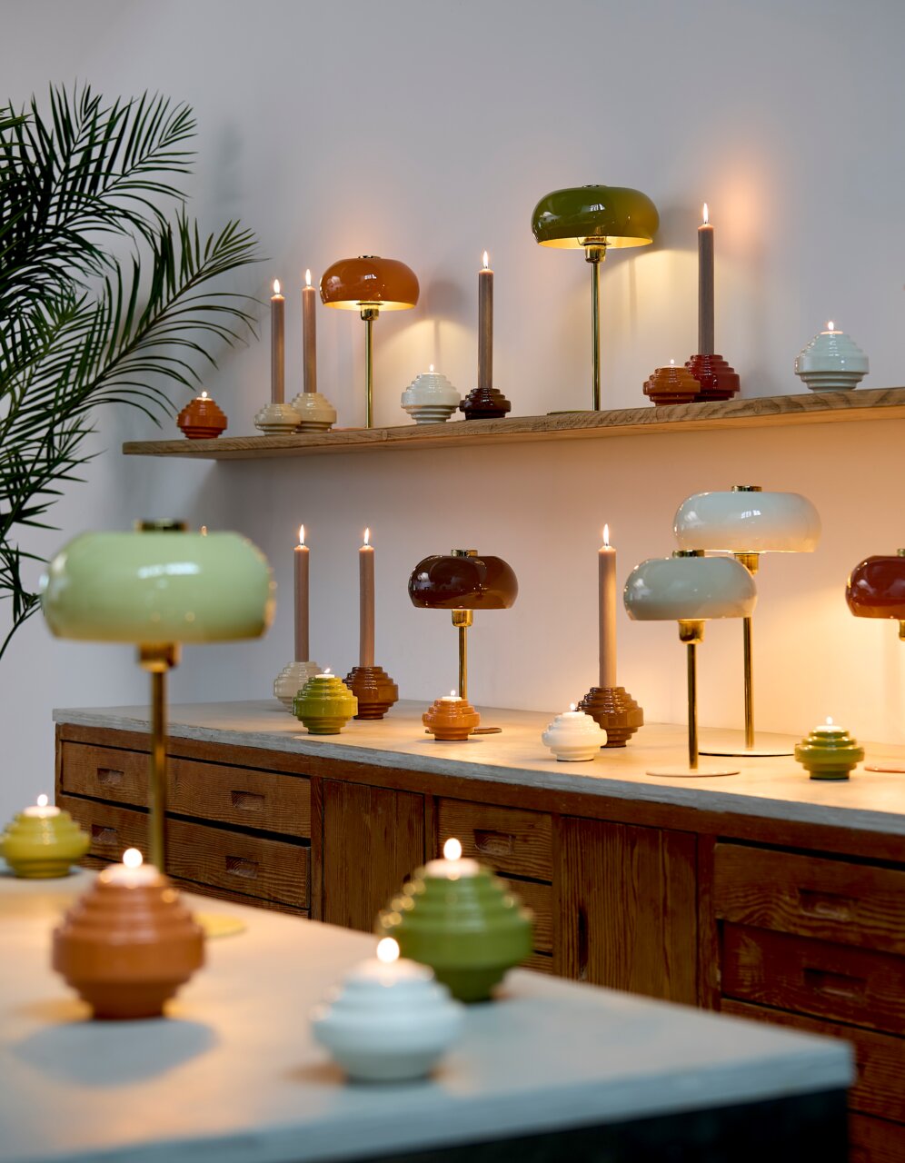 Light&Living Tischleuchte SURIN Mehrere Tischleuchten in verschiedenen Farben und Formen auf einem Regal und Tisch, seitliche Perspektive.