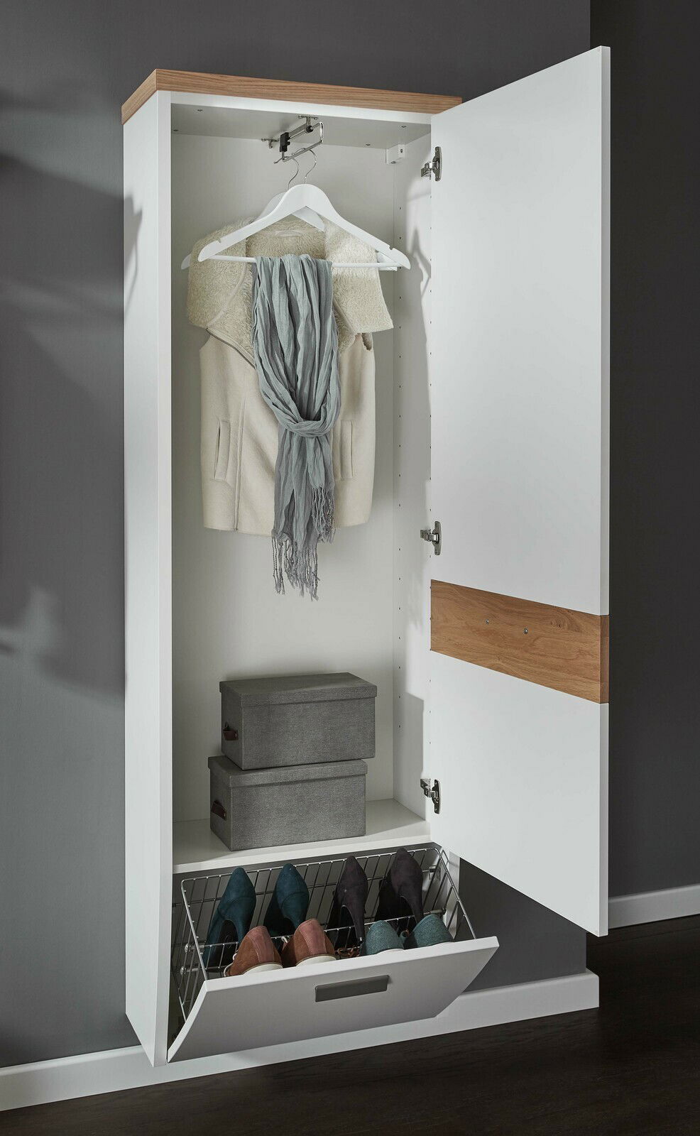 Hängegarderobenschrank mit geöffneter Tür, zeigt Kleiderbügel mit Jacke und Schal, zwei graue Aufbewahrungsboxen und ein Schuhregal mit Schuhen, Perspektive von vorne.