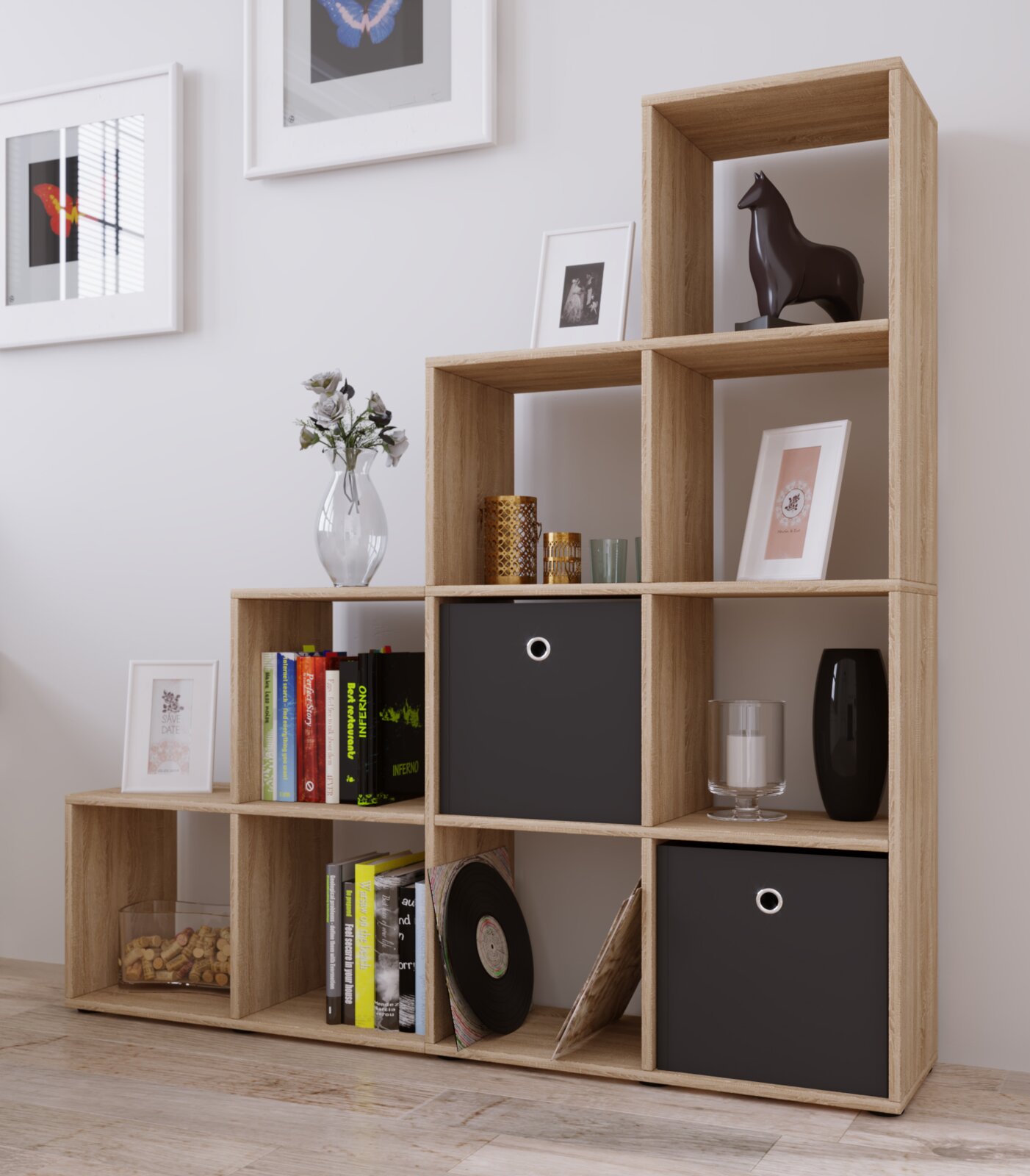 Modulares Stufenregal aus Holzdekor mit offenen Fächern und zwei schwarzen Aufbewahrungsboxen, dekoriert mit Büchern und Vasen, in Frontansicht mit leichter Schrägperspektive von rechts.