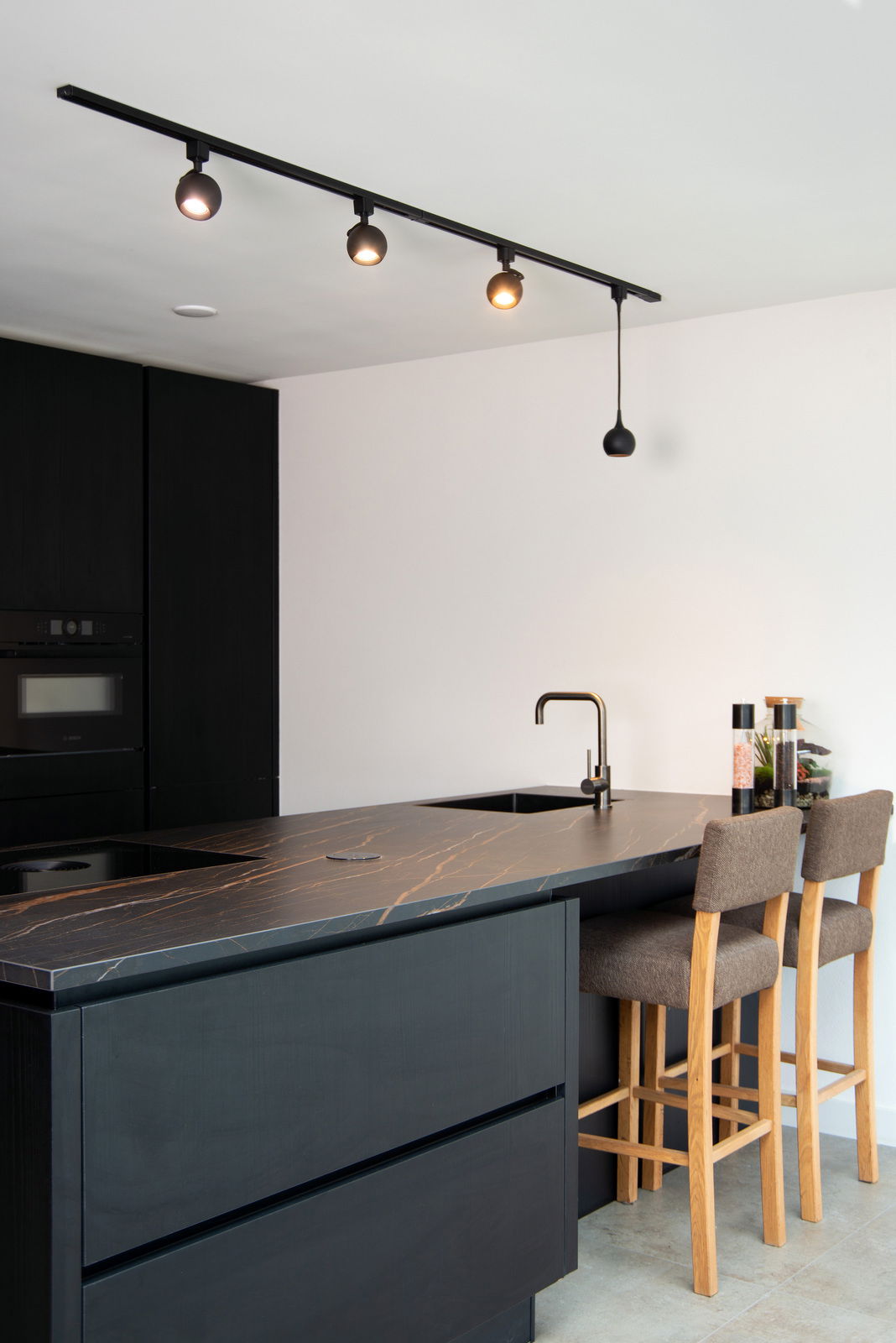 Moderne schwarze Strahler auf einer Schiene in einer stilvollen Küche, seitliche Perspektive.