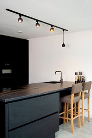 Moderne schwarze Strahler auf einer Schiene in einer stilvollen Küche, seitliche Perspektive.