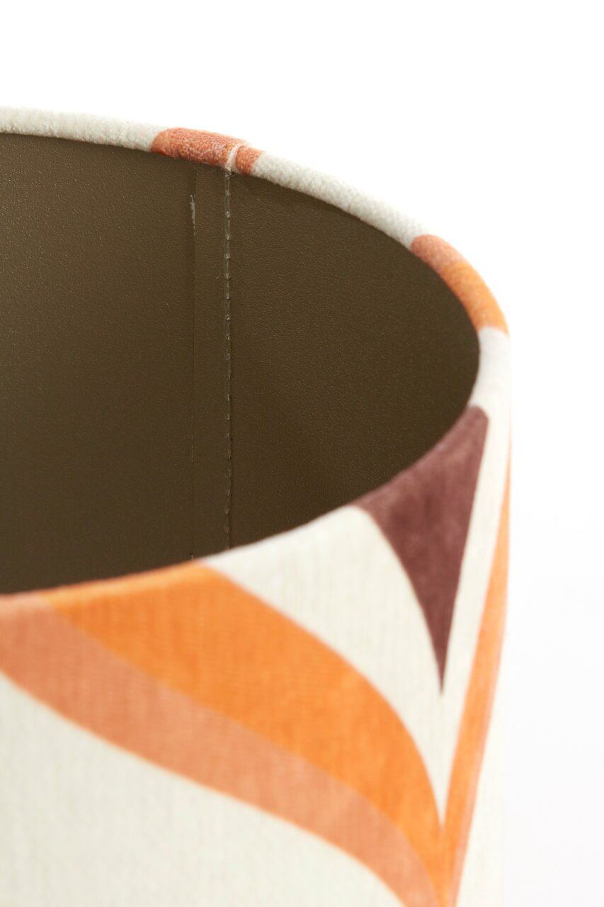 Close-up van een lampenkap met een geometrisch patroon in oranje- en bruintinten, gezien vanuit de zijkant.