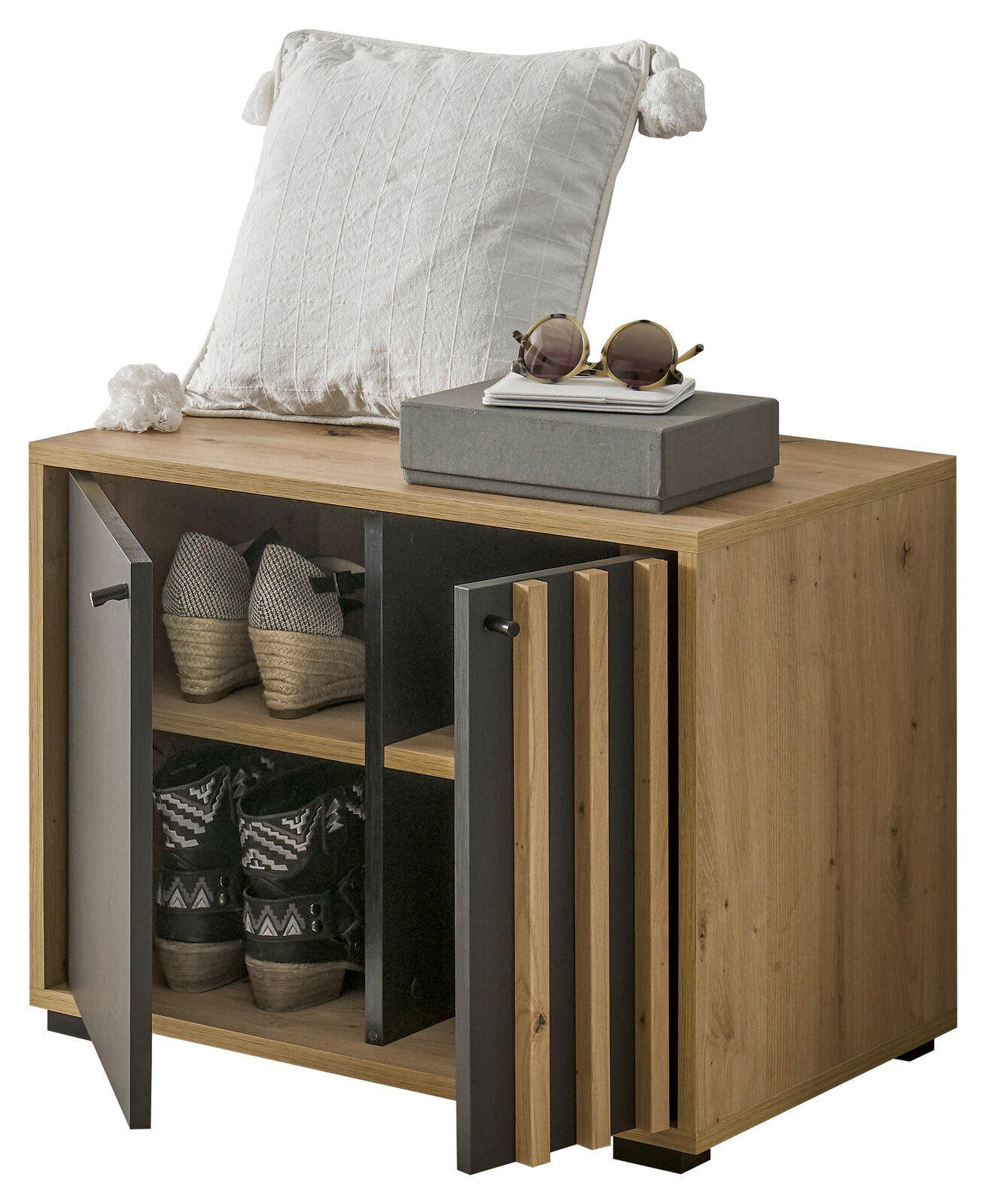 Garderobenbank aus Holz mit zwei offenen Türen, die Schuhe auf zwei Ebenen zeigen. Obenauf liegt ein weißes Kissen und eine Sonnenbrille. Perspektive von vorne links.