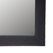 Nahaufnahme eines rechteckigen Spiegels mit dunklem, strukturiertem Rahmen, perspektivisch von der Ecke aus gesehen.