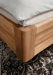 Nahaufnahme eines Massivholzbettgestells aus Eiche mit abgerundeten Ecken, von oben betrachtet.