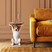 Beistelltisch mit Hundeskulptur als Basis, aus der Perspektive von vorne neben einem gelben Sofa.