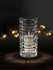 Kristallklare Vase oder Windlicht mit strukturiertem Muster, beleuchtet von einer Kerze, auf dunklem Hintergrund, frontal betrachtet.