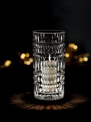 Kristallklare Vase oder Windlicht mit strukturiertem Muster, beleuchtet von einer Kerze, auf dunklem Hintergrund, frontal betrachtet.