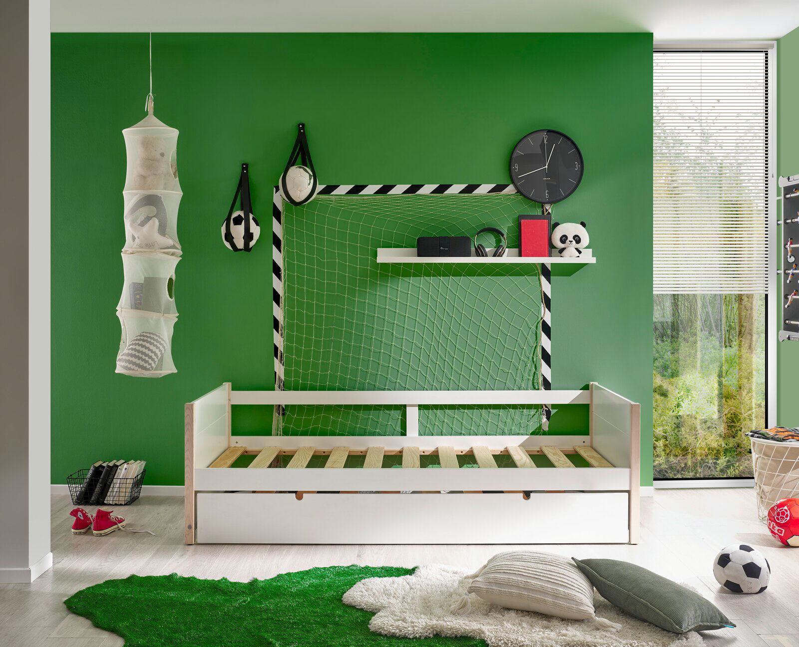 Jugendbett in einem sportlich dekorierten Zimmer mit grüner Wand, Fußballthema und Blick auf das Bett von vorne.