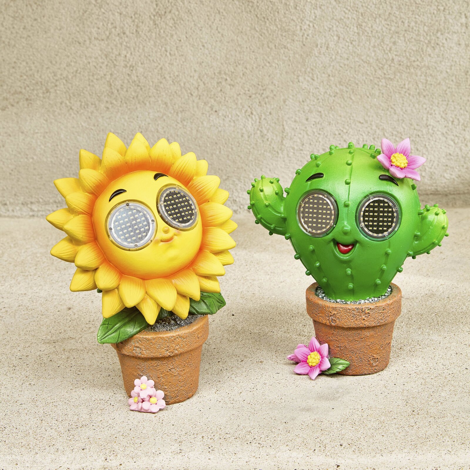 Twee zonnefiguren van hars in bloempotten: een gele zonnebloem en een groene cactus met bloemen, van voren gefotografeerd.