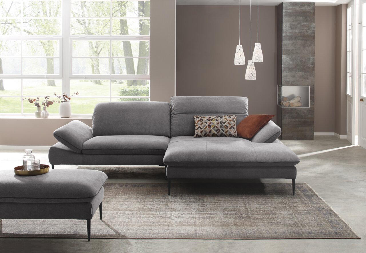 Grijze longchair-set in een moderne woonkamer, zijaanzicht met grote ramen op de achtergrond.