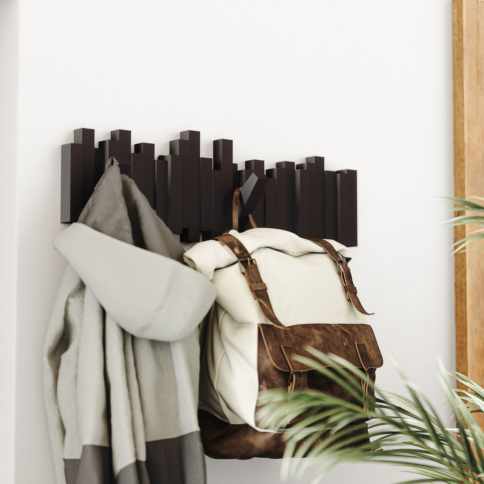 Moderne Wandgarderobe mit geometrischem Design, von der Seite betrachtet, mit aufgehängtem Mantel und Rucksack.