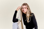 Een vrouw in sportkleding houdt een beige sporthanddoek tegen haar voorhoofd, gezien vanuit de zijkant.