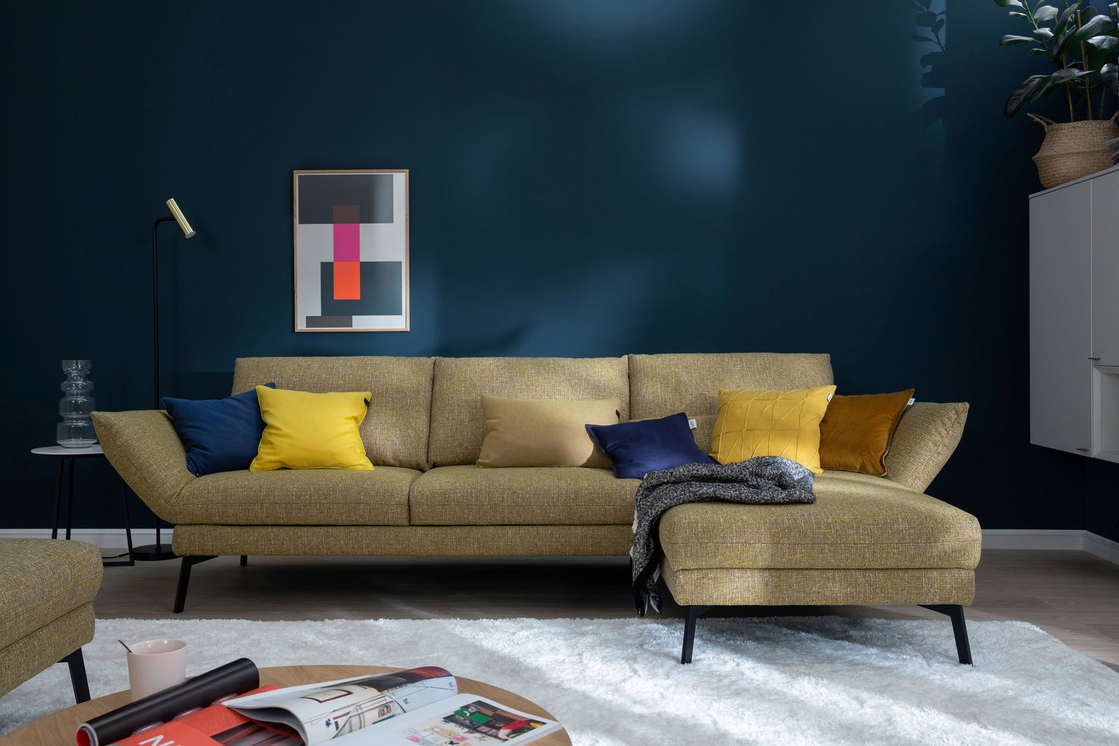 Moderne Longchairkombination in senfgelber Farbe mit bunten Kissen, frontal fotografiert in einem stilvoll eingerichteten Wohnzimmer.