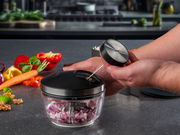 Multizerkleinerer ZIZO auf einer Küchenarbeitsplatte, gefüllt mit gehackten Zwiebeln, umgeben von frischem Gemüse. Perspektive von oben.