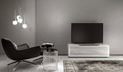 Modernes Wohnzimmer mit TV-Lowboard in Weiß, frontal betrachtet, neben einem schwarzen Sessel und einem Beistelltisch.