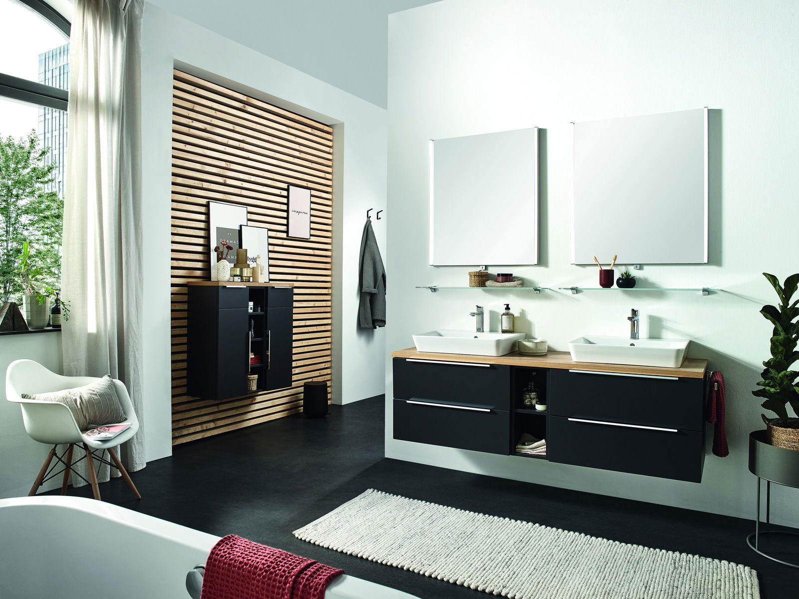 Moderne Badkombination mit zwei Waschbecken, schwarzen Unterschränken und großen Spiegeln, seitliche Perspektive.