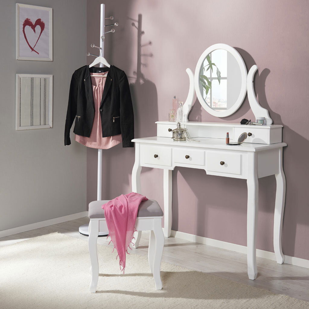 Weißer Schminktisch mit ovalem Spiegel und drei Schubladen, frontal fotografiert, mit passendem Hocker und dekorativen Accessoires.