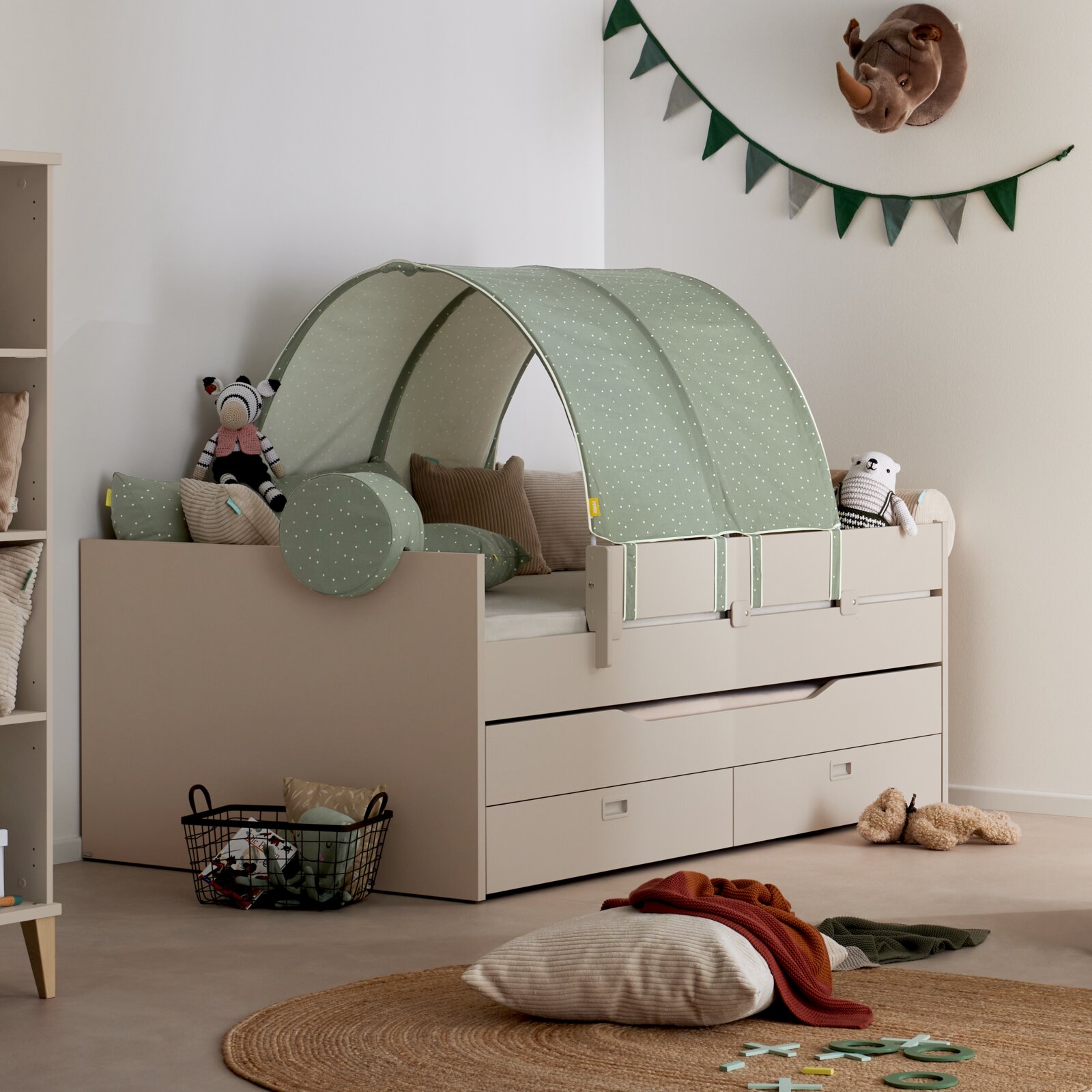 Kinderbett mit mintgrünem Betthimmel/Baldachin mit weißen Punkten und passenden Kissen im Kinderzimmer, seitliche Perspektive von schräg vorne