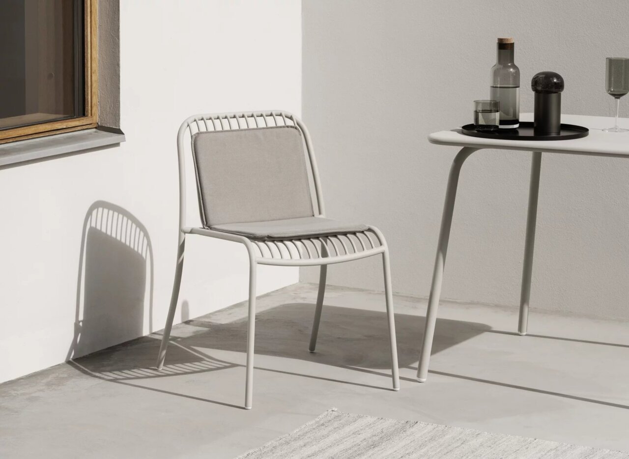 blomus Tablett L PEASY Moderner weißer Stuhl mit grauem Kissen auf einer Terrasse, seitliche Perspektive
