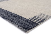 Nahaufnahme eines Frisé-Teppichs mit grauen und beigen Streifen, perspektivisch von der Seite aufgenommen.