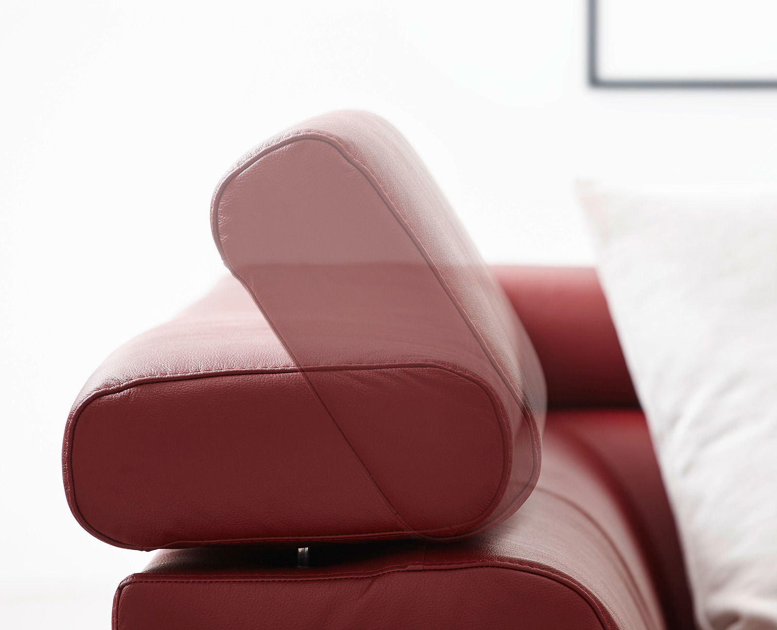 Nahaufnahme einer roten Ledercouch mit verstellbarer Kopfstütze, seitliche Perspektive.