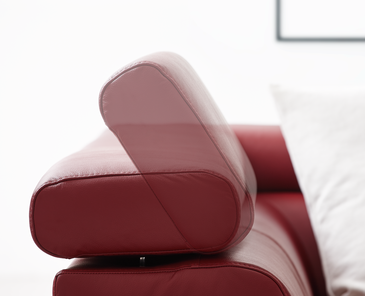 Nahaufnahme einer roten Ledercouch mit verstellbarer Kopfstütze, seitliche Perspektive.