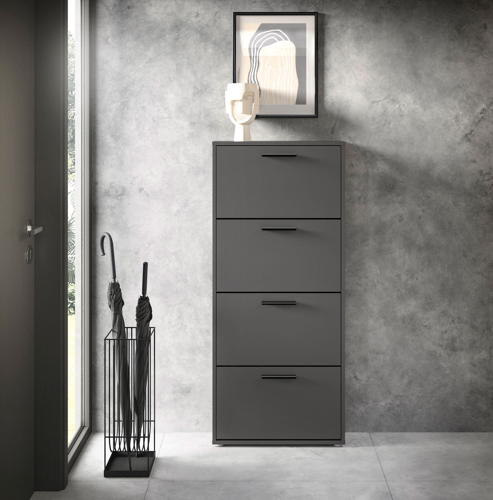 Moderner Schuhkipper mit vier Klappen in dunklem Grau, frontal fotografiert, neben einem Regenschirmständer und dekoriert mit einem Kunstobjekt und einem Bild an der Wand.