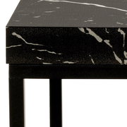 Nahaufnahme eines Couchtischs mit schwarzer, marmorierter Oberfläche und schwarzem Metallgestell, seitliche Perspektive.