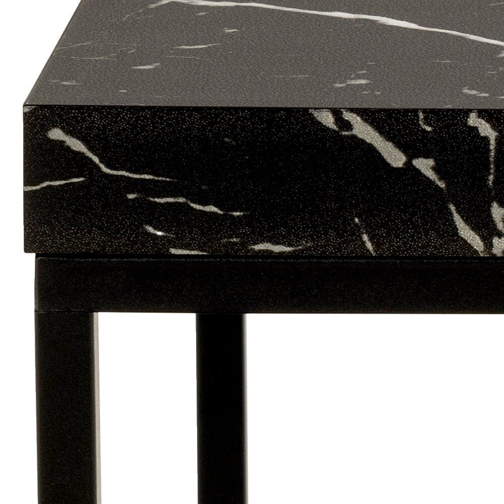 Nahaufnahme eines Couchtischs mit schwarzer, marmorierter Oberfläche und schwarzem Metallgestell, seitliche Perspektive.