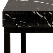 Nahaufnahme eines Couchtischs mit schwarzer, marmorierter Oberfläche und schwarzem Metallgestell, seitliche Perspektive.