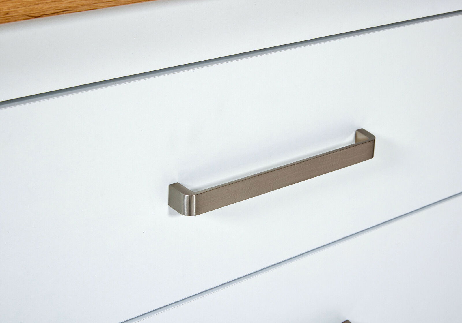 Nahaufnahme einer Küchenschublade mit modernem, rechteckigem Metallgriff in seitlicher Perspektive.