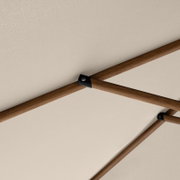 Detailfoto van onderaf: houten onderstel met kruissteunen en zwarte metalen verbindingsstukken onder een lichtgekleurd tafelblad