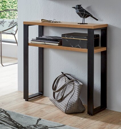 Schmaler Konsolentisch im Industrial-Design mit Holzoptik-Ablageflächen und schwarzem Metallgestell an einer grauen Wand, mit Deko und Tasche darunter, fotografiert in frontaler leicht seitlicher Perspektive.
