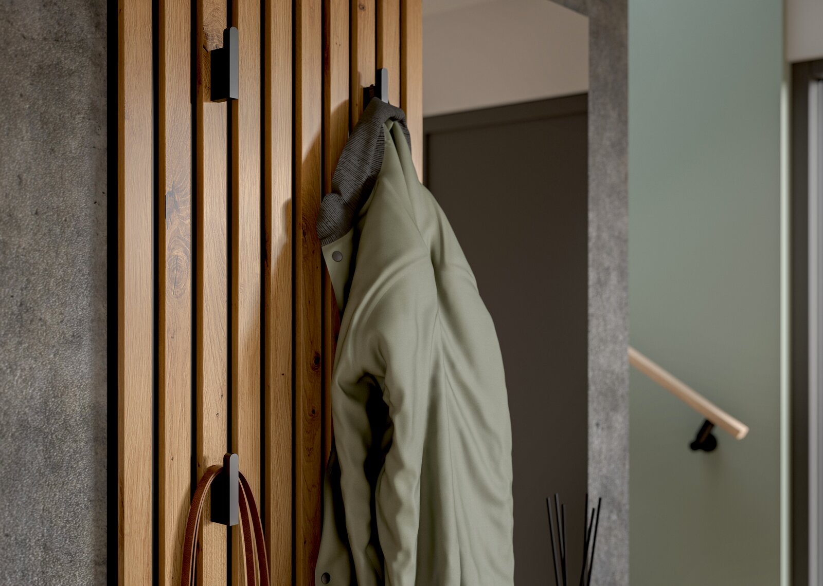 Nahaufnahme einer Kompaktgarderobe aus Holz mit mehreren Haken, an denen eine grüne Jacke hängt. Perspektive von der Seite.