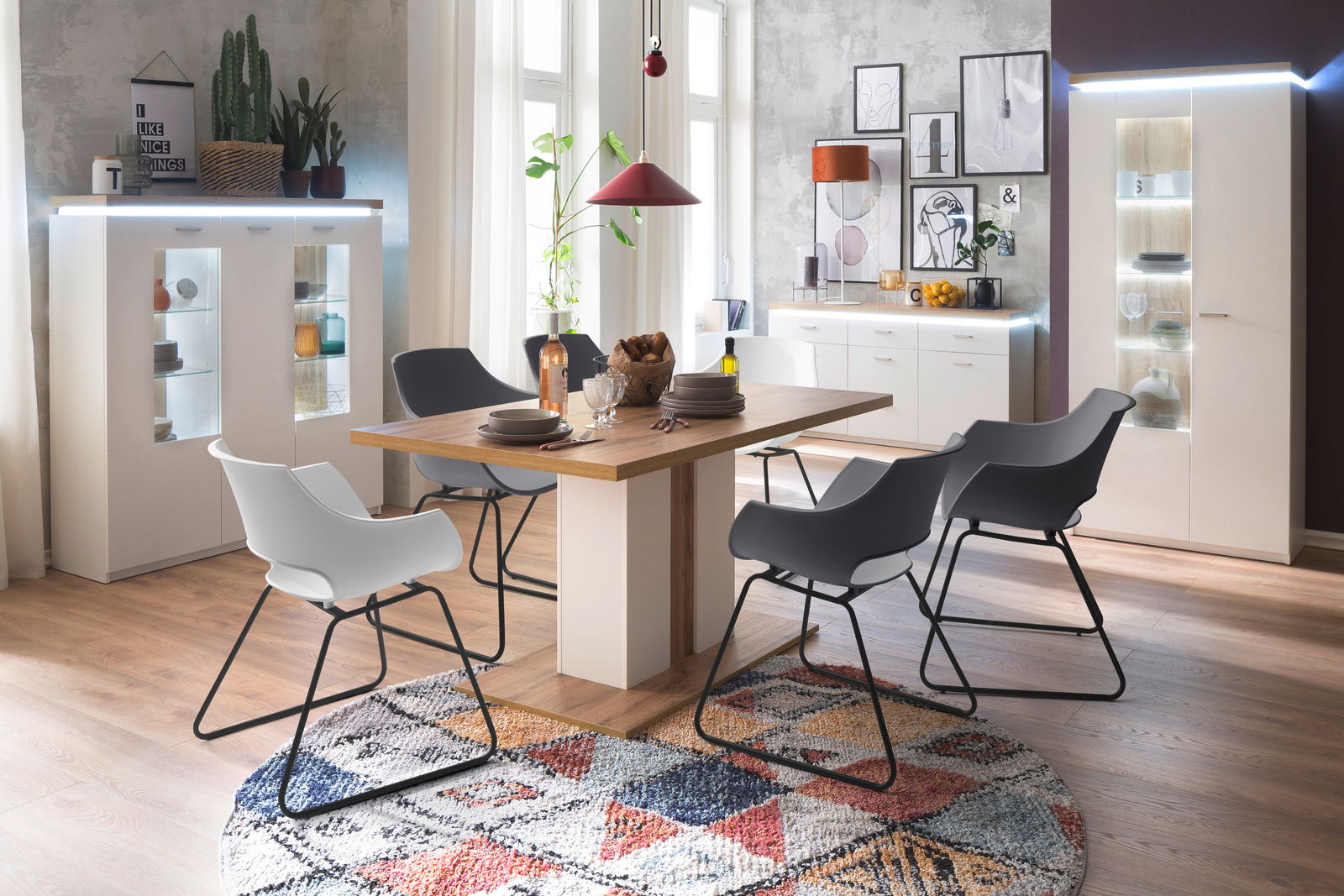 Esszimmer mit modernem Esstisch und Stühlen, umgeben von stilvollen Vitrinen und Sideboards, Perspektive von vorne.