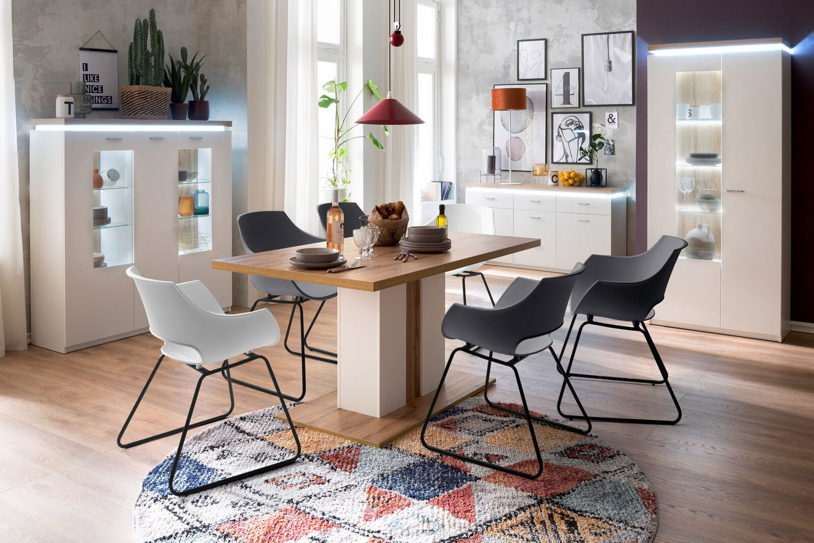 Esszimmer mit modernem Esstisch und Stühlen, umgeben von stilvollen Vitrinen und Sideboards, Perspektive von vorne.