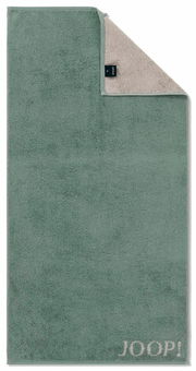 Grünes Handtuch mit beiger Rückseite und aufgesticktem 'JOOP!' Logo, aus der Vogelperspektive fotografiert.