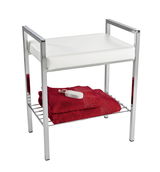 Moderner Badhocker mit weißem Sitzpolster und verchromtem Gestell, darunter ein Regal mit roten Handtüchern und Bimsstein, seitliche Perspektive.