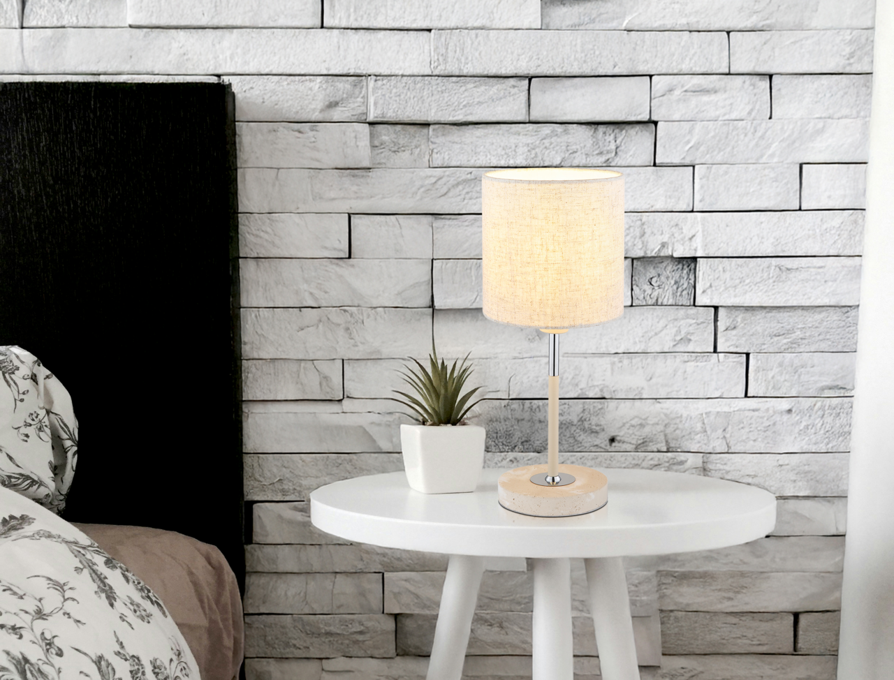 Globo Lighting Tischleuchte DELEON Tischleuchte auf einem weißen runden Tisch, neben einer kleinen Pflanze, vor einer weißen Ziegelwand. Perspektive: seitlich.