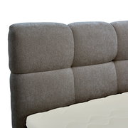 Nahaufnahme eines gepolsterten Boxbett-Kopfteil in grauer Farbe, seitliche Perspektive