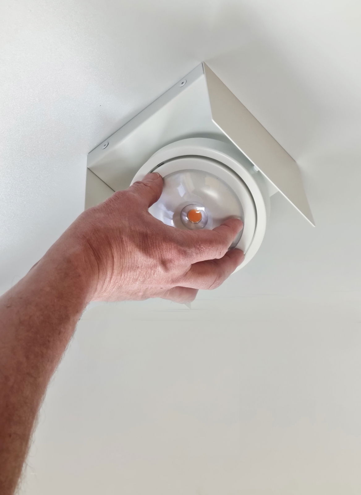 Hand montiert eine LED Aufbauleuchte an der Decke, seitliche Perspektive.