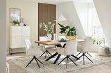 Moderner Esstisch mit Holzplatte und schwarzen Metallbeinen, umgeben von weißen Polsterstühlen in einem hellen, stilvoll eingerichteten Raum. Perspektive von der Seite.